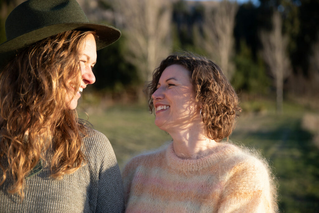 Two women smile at each other lovingly.